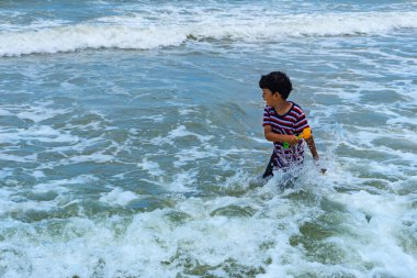 Asyalı çocuk yaz tatillerinde Phala Sahili, Ban Chang Bölgesi, Rayong, Tayland 'da oynamaktan zevk alıyor..