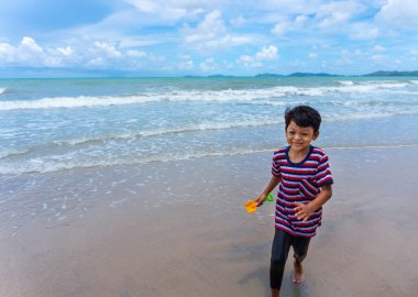 Asyalı çocuk yaz tatillerinde Phala Sahili, Ban Chang Bölgesi, Rayong, Tayland 'da koşu yapıyor ve hayatın tadını çıkarıyor..