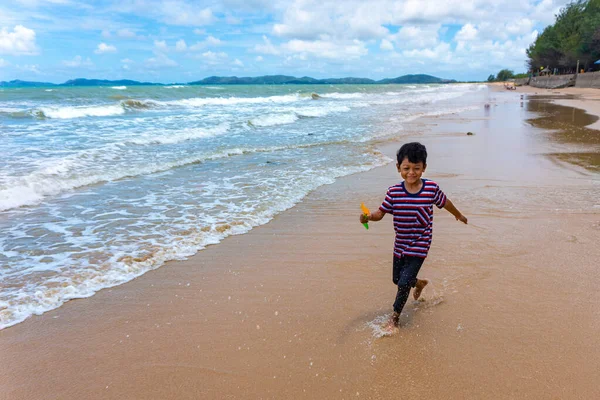 Asyalı çocuk yaz tatillerinde Phala Sahili, Ban Chang Bölgesi, Rayong, Tayland 'da koşu yapıyor ve hayatın tadını çıkarıyor..