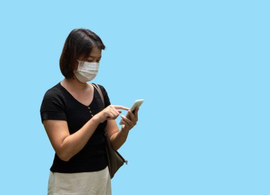 Genç Asyalı kadın akıllı telefon kullanıyor ve yüz maskesi takıyor. Sağlık hizmetleri konsepti için Coronavirus 'u (COVID-19) koruyor.
