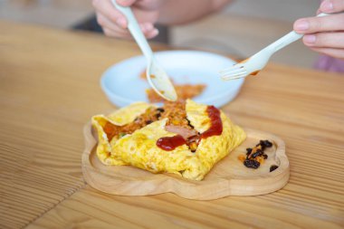 Domuz etiyle sarılmış omlet ve ahşap bir tabağa yerleştirilmiş kızarmış sos.