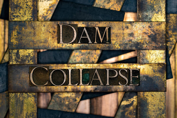 Dam Collapse text formed with real authentic typeset letters on vintage textured silver grunge copper and gold background