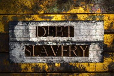 Debt Slavery text formed with real authentic typeset letters on vintage textured silver grunge copper and gold background clipart
