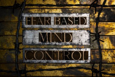 Fear based Mind Control metni, klasik desenli gümüş grunge bakır ve altın arkaplan üzerine dikenli tel ile gerçek otantik yazı dizisi harfleriyle oluşturuldu.