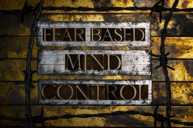 Fear Based Mind Control text formed with real authentic typeset letters with barbed wire on vintage textured silver grunge copper and gold background clipart