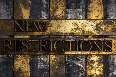 New Restrictions text message authentic on textured grunge copper and vintage gold background clipart