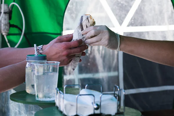 A man gets a wrap served at a street food market.