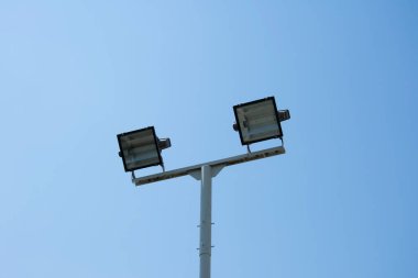 Arka planda mavi gökyüzü olan çift halojen sokak lambası