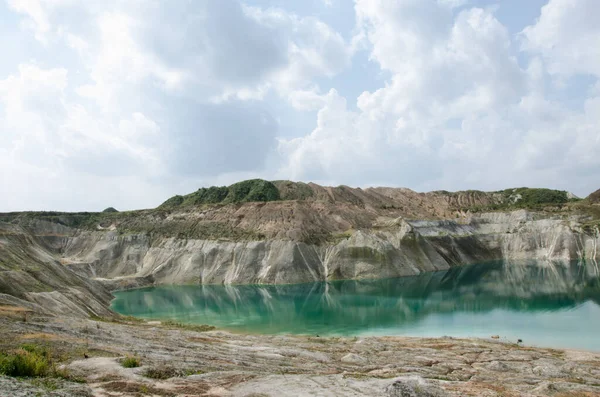 Emerald water at the foot of chalk hills. Sheer walls of the chalk quarry. Chalk quarry steps flooded by emerald water. Belarussian maldives