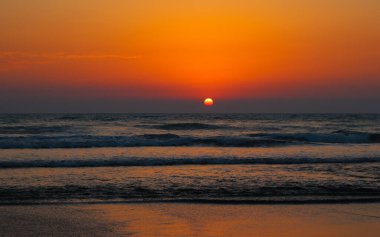 Mavi okyanusun üzerinde güzel bir gün batımı. Suyun rengini yansıtan renkli bir gökyüzü..
