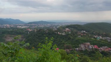 Sept,4th205 Dehradun India. A panoramic view of dehradun's outskirts , a lush green landscape with hills and scattered houses under a cloudy sky. deforestation and Urban development.