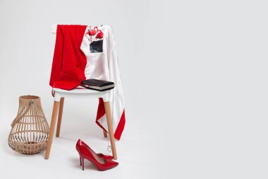 Sandalyede kırmızı moda bir ceket, zincirli bir çanta, kırmızı ayakkabılar ve hasır bir sepet. Modaya uygun bir görüntü. Metin için arkaplan alanı. Bir moda dergisinde illüstrasyon.