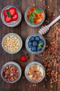 Çilek, yabanmersini, kurutulmuş kayısı, musli, tarçınlı muz, ballı sedir fıstığı. Kırsal ahşap arka plan solgunluk ve musli