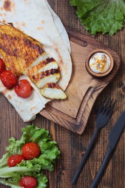 Çiğ fileto ızgara ve biraz karri ve pide. Kızarmış kiraz domatesleri meze olarak kullanılıyor. Tahta kesme tahtası, tahta masa. Kara çatal bıçağı.