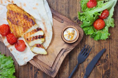 Çiğ fileto ızgara ve biraz karri ve pide. Kızarmış kiraz domatesleri meze olarak kullanılıyor. Tahta kesme tahtası, tahta masa. Kara çatal bıçağı.