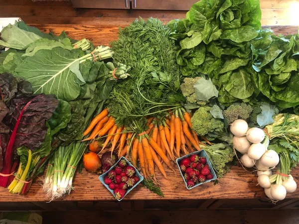 Spring garden produce harvest is laid out on a rustic wooden table in a historic farmhouse kitchen. Fresh new life, wholesome, healthy eating concepts as well as community garden themes with copy space.