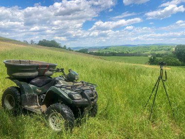 Çimenli tarımsal alanda mavi gökyüzü arka planı ve kopyalama alanı üzerinde off road aracı ve kamera tripod.