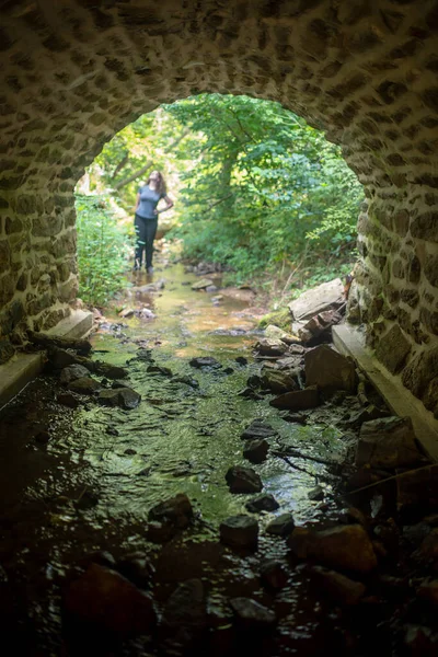 Abstrakte Frau durch Tunnel an Waldbach im defokussierten Hintergrund — Stockfoto