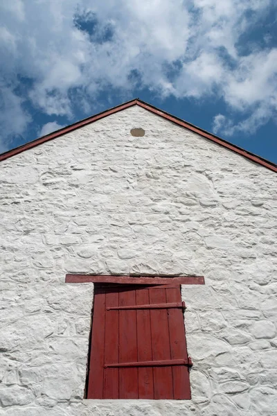 Kırmızı kepenk, antika menteşeler ve eski çiftliğin sivri uçlu çatısı.. — Stok fotoğraf