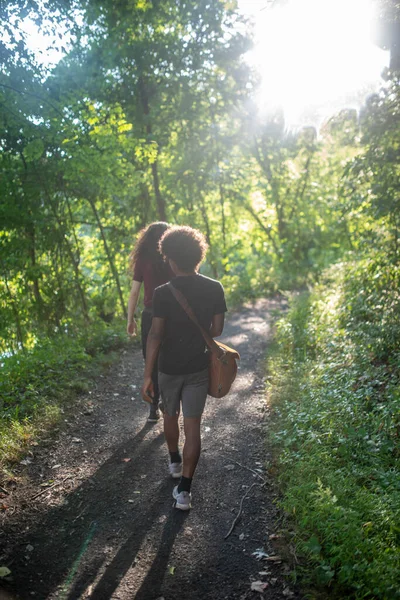 Jonge Afro-Amerikaanse en Kaukasische mannen wandelen bospad. — Stockfoto