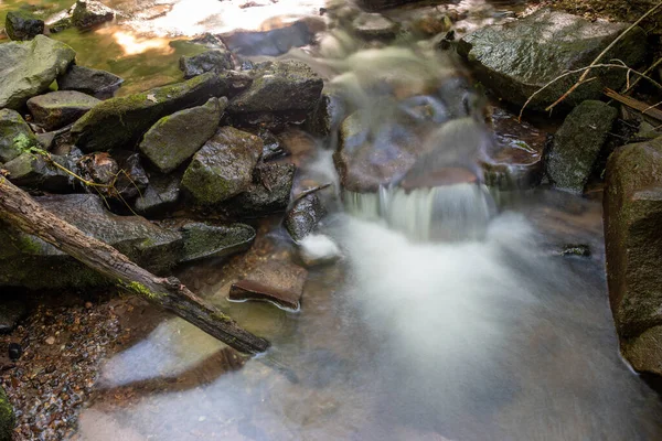 Długa ekspozycja wodospadu leśnego rozlewającego się na kamienie. — Zdjęcie stockowe