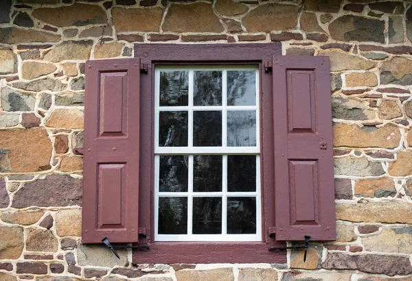 Renkli taş evdeki 12 camlı koloni penceresi ve kırmızı panjurlar. — Stok fotoğraf
