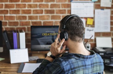 Bir ofiste bilgisayar kullanarak kulaklık Beyaz adam arkadan görünüş