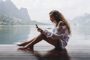 Telefonunu bir göl kenarında kullanan kadın