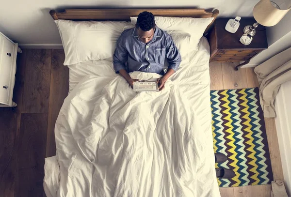 Άνθρωπος Στο Κρεβάτι Μια Ψηφιακή Συσκευή — Φωτογραφία Αρχείου