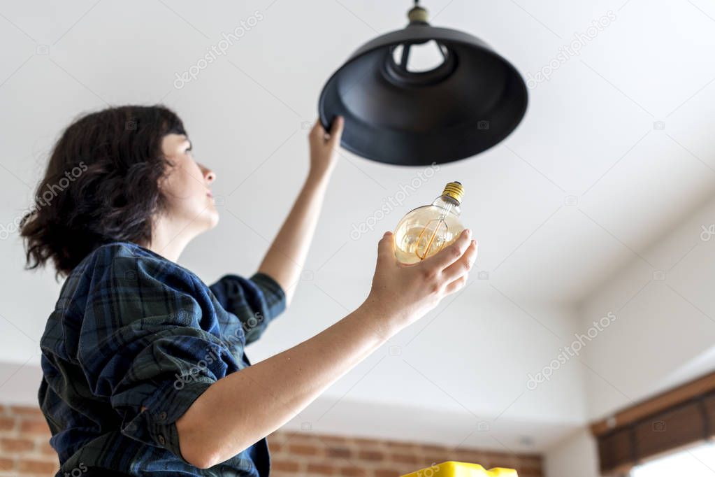 Woman changing lightbulb at home 
