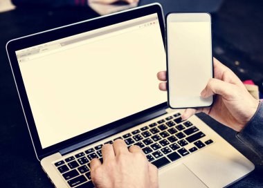 kısmi masada beyaz monitör ekran ile cep telefonu tutan insan el görünümünü