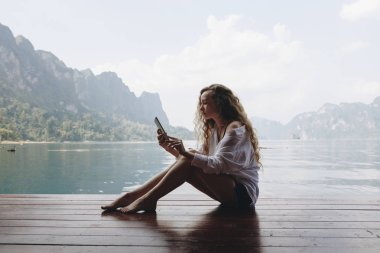 Telefonunu bir göl kenarında kullanan kadın