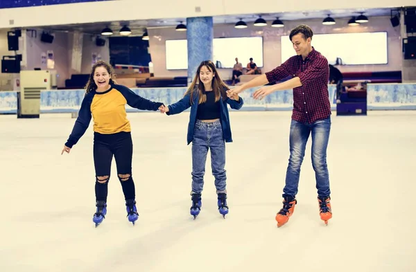 Group of teenage friends ice skating on the ice rink together