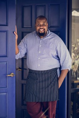 Afrika erkekte neşeli önlük ayakta kapıda, küçük işletme sahibi
