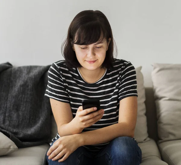 Smartphone kullanarak bir kanepede oturan kadın