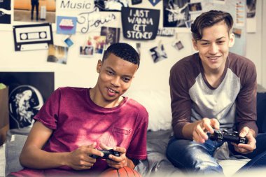 Genç çocukların birlikte video oyunları oynarken bir yatak odasında takılmak