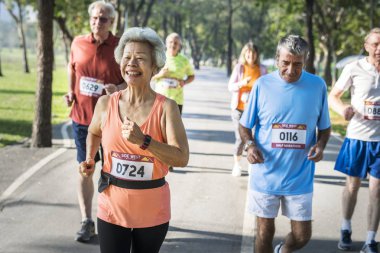 Park'ta jogging ve gülümseyen kıdemli sporcular 