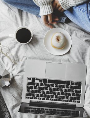 yatakta kahve ve kek ile bilgisayar dizüstü kullanan kadın üstten görünüm 