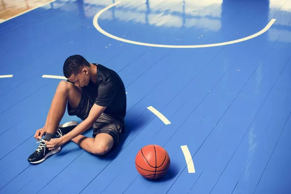 Afrikanisch Amerikanischer Teenager Bindet Seine Schnürsenkel Auf Einem Basketballfeld — Stockfoto