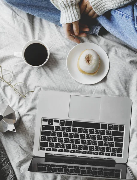 yatakta kahve ve kek ile bilgisayar dizüstü kullanan kadın üstten görünüm 