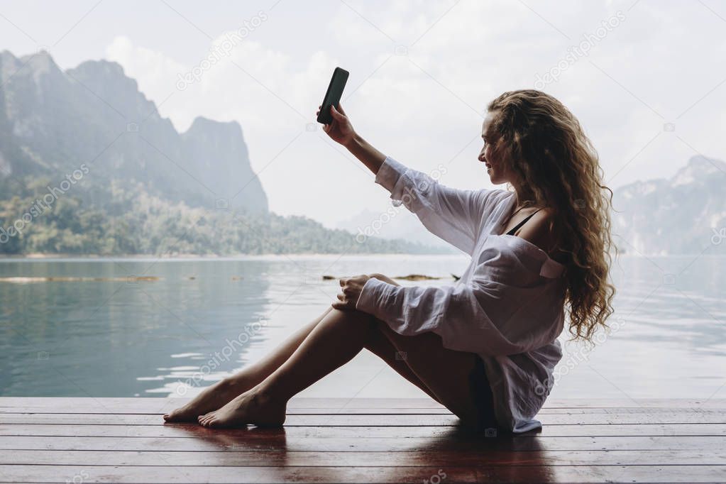 Woman using her phone by a lake