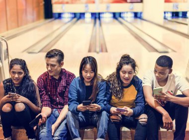 Genç arkadaş bir bowling salonu smartphone kullanarak grubu