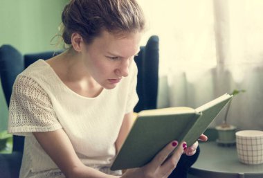 Evde kitap okuyan bir kız.