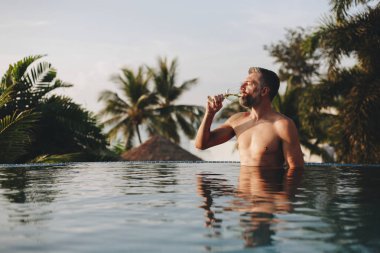 Bir bardak şarap havuza sahip yakışıklı adam