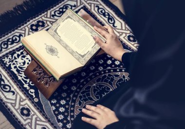 Müslüman kadın siyah türban Kur'an, okuduktan kırpılmış görüntü