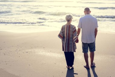 Olgun kadın ve kumsalda yürüyen adam görünümünü geri 