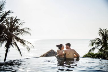 Couple relaxing in a swimming pool clipart