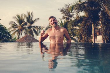 Bir bardak şarap havuza sahip yakışıklı adam