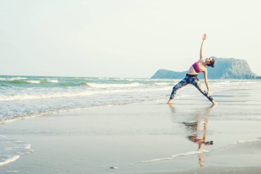 Kadın plajda yoga yapıyor.