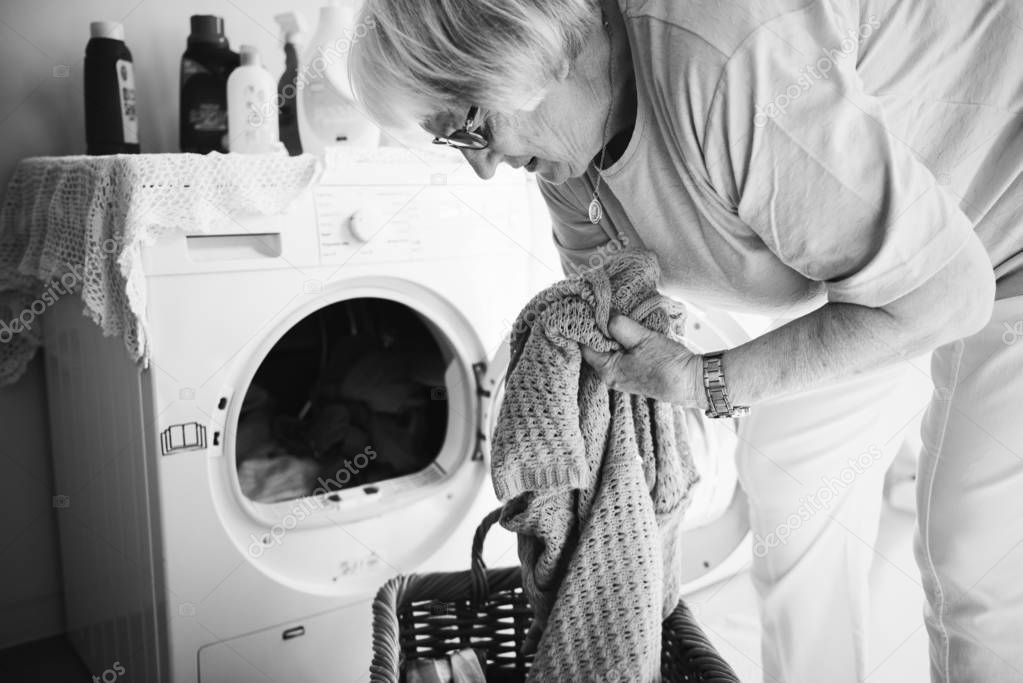 Elderly woman doing laundry at home